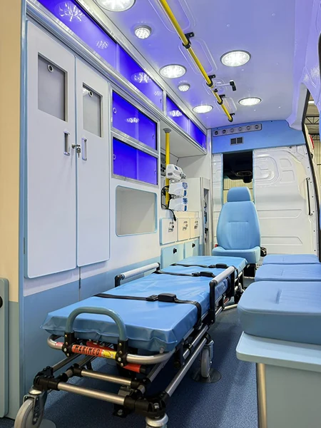 Interior de ambulância com maca azul, armários e iluminação no teto