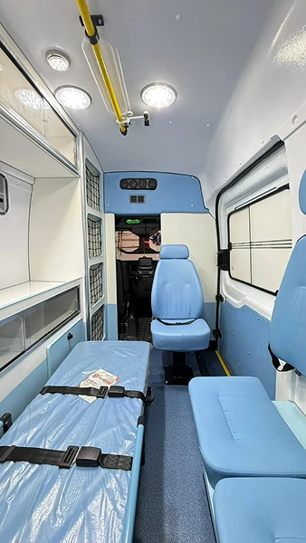 Maca, banco lateral e poltrona azuis no interior de uma ambulância