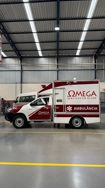 Vista lateral de ambulância branca e vermelha com módulo de atendimento