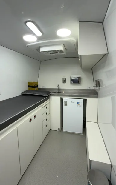 Interior de unidade móvel com bancada, armários, pia e refrigerador