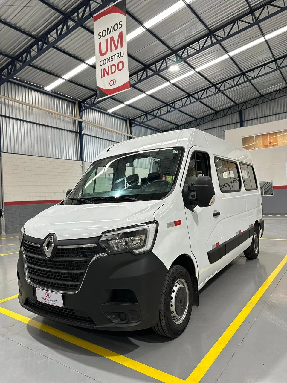 Van branca Renault para transporte de passageiros em vista frontal e lateral
